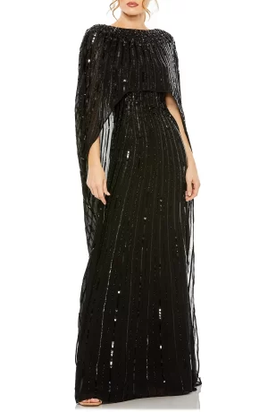 A woman stands wearing a MAC DUGGAL Sequin Embellished Long Sleeve Capelet Column Gown. The dress is fitted and designed with vertical sparkling stripes, expressing elegance and sophistication.