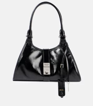 A Prada Medium Leather Shoulder Bag in black patent leather, featuring silver hardware, a top handle, front flap with push-lock closure, and a hanging leather tag with key attached.