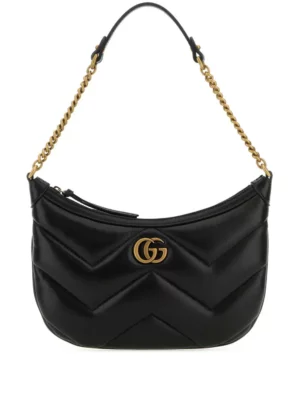 A black quilted leather Gucci Lion GG Handbag with a gold chain strap, gold GG logo emblem on the front, and a zippered closure at the top.