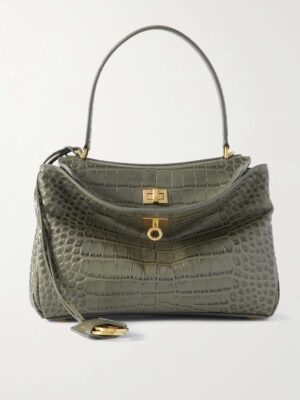 A medium-sized, gray-green croc-leather tote with a single top handle, gold hardware, and a flap closure with a lock. The bag has a structured shape and a leather tag attached by a strap.