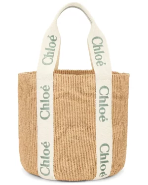 A woven beige tote bag with two thick white handles, featuring the green word "Chloé" printed in all caps down each strap. Inspired by the Chloe Bracelet Bag, it has a simple rectangular shape and no visible closures or compartments.