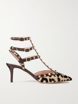 A pointed-toe, mid-heel shoe inspired by the Valentino Garavani Hi Dolly Patent-leather Pumps. It features a striking leopard print, three black leather ankle straps with gold buckles, and gold pyramid studs along the straps and edges.