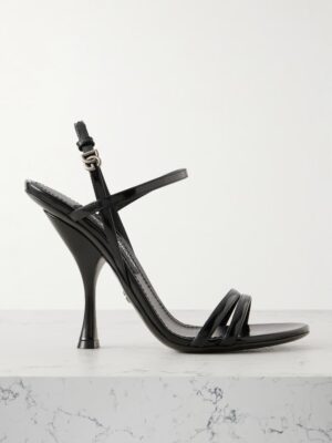 A black patent leather high-heeled sandal with a curved stiletto heel, thin toe and ankle straps, and a silver buckle evokes the elegance of Dolce & Gabbana Patent-Leather Mary Jane Pumps, displayed on white marble against a light background.