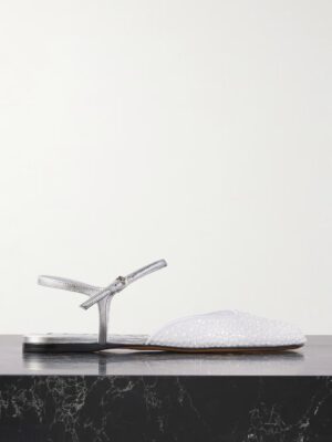 A silver flat sandal inspired by Loewe Paula's Ibiza Petal Leather Sandals, featuring an ankle strap and a closed, textured white toe, displayed on a black marble surface against a plain white background.