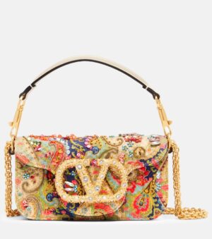 A paisley-patterned Valentino Garavani Locò Small Embellished Metallic Leather Shoulder Bag with multicolored embellishments, a large gold crystal-accented clasp, a short black-and-white handle, and a gold chain shoulder strap.