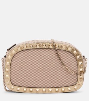 A small oval-shaped beige Valentino Garavani Medium Studded Leather Shoulder Bag, featuring a gold chain strap, gold studded trim, and a checkered fabric pattern.
