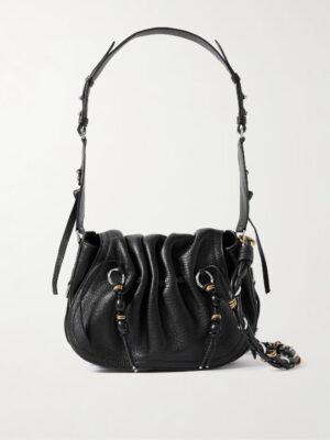 A black leather handbag inspired by the Isabel Marant Bolton Embellished Tasseled Textured-leather Shoulder Bag, featuring a ruched design, metal ring accents, a wide adjustable strap, and decorative knotted details. Set against a plain white background.