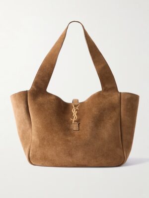 A large brown Saint Laurent Le ร 7 Bea Suede Tote with wide shoulder straps and a gold YSL logo charm hanging from the front. The bag features a minimalist design and a slightly curved top edge.