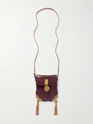 A small, dark brown Chloé Château Treasures Embellished Textured-leather Shoulder Bag with a gold clasp, decorative gold detailing on the corners, a long twisted strap, and two beige tassels hanging from the bottom corners.