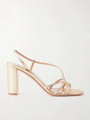 An Aquazzura Talk to Me Metallic Leather Sandal is shown in side profile against a plain white background, featuring a gold, minimalist design with thin straps, an ankle strap, and a chic block heel.