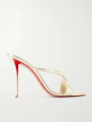 A gold Christian Louboutin Mulazee Cross Metallic Leather Mule sandal with crisscross straps and a signature red sole, photographed from the side against a plain white background.