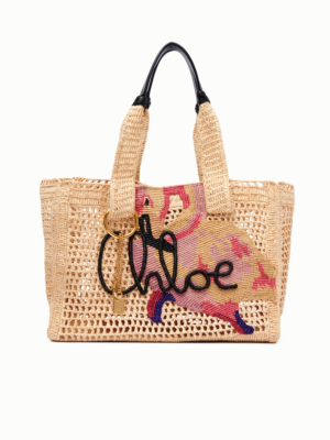 A woven straw tote bag with two handles, featuring a colorful embroidered horse, the word "Chloe" in black script, and a gold keychain—reminiscent of the Chloe Summer Banana Hobo Bag in Raffia—set against a plain white background.