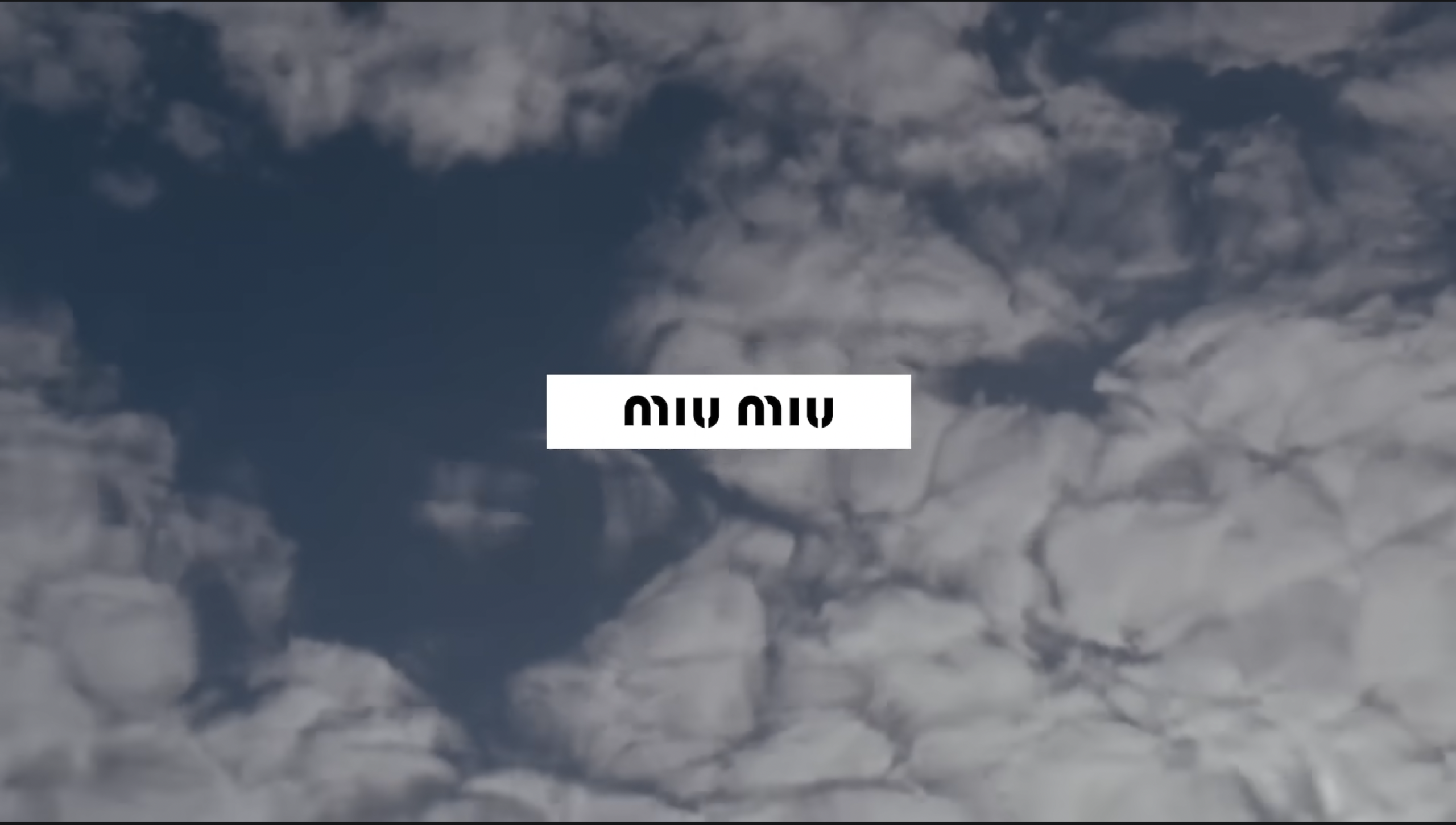 A cloudy sky with a rectangular white box in the center containing the text "miu miu" in lowercase, stylized black font.