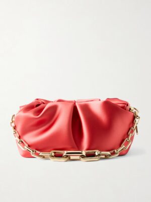 A red satin clutch bag with a gold chain handle, shown against a plain white background. Reminiscent of the Christian Louboutin Loubi54 Sirene Snakeskin Leather Wallet on Chain, its fabric is softly gathered at the top, giving a ruched effect.